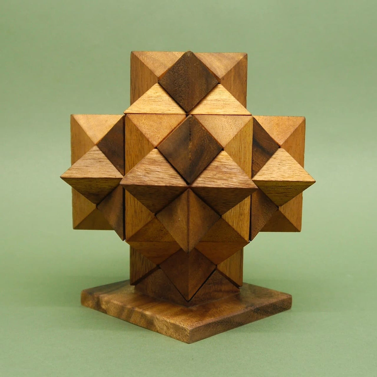 Geduldsspiel: Ein komplett zusammengesetztes Sternpuzzle bildet ein geometrisches Holz­kreuz auf einem quadratischen Sockel.