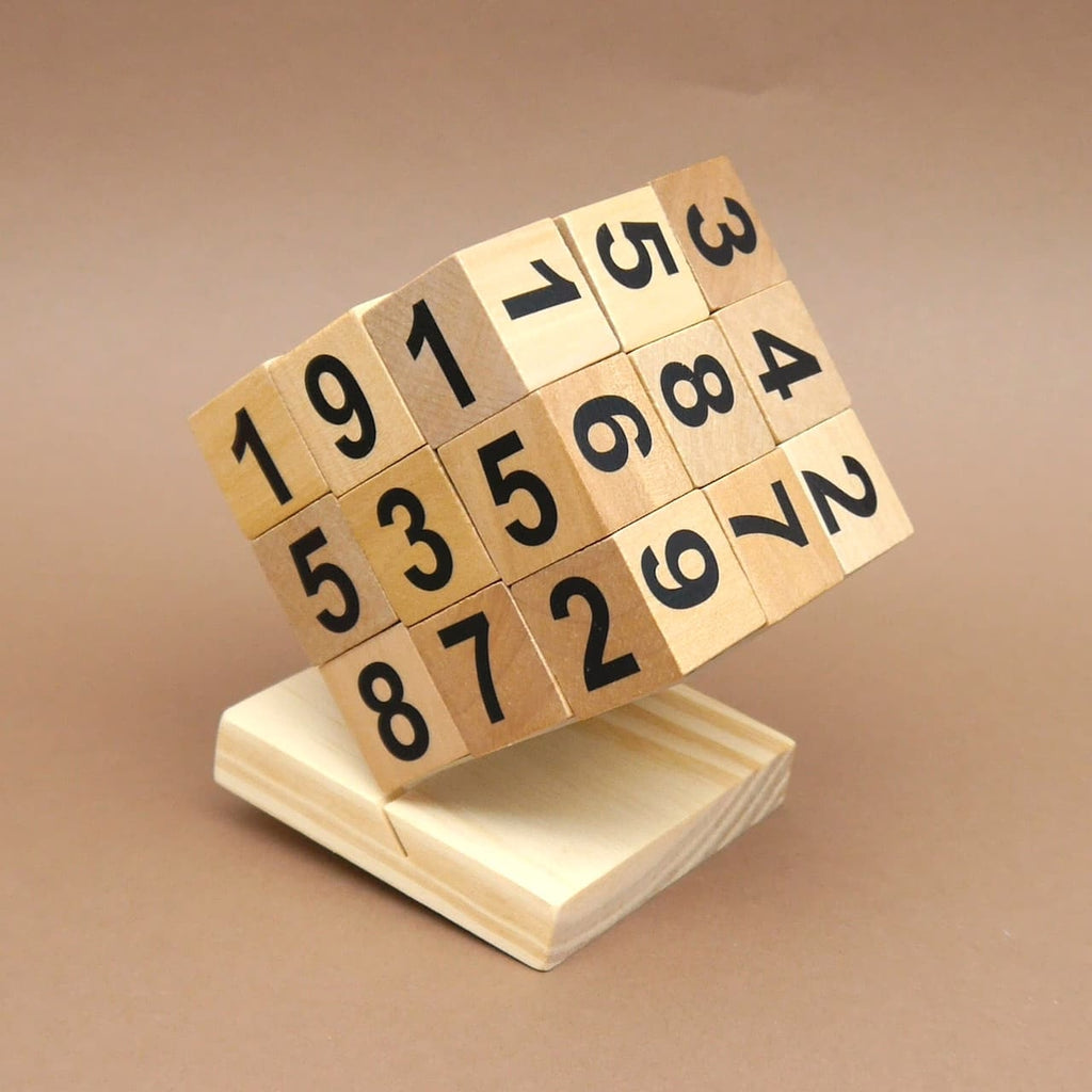Auf einem Holzsockel schräg stehendes Sudoku Zahlenpuzzle aus Holz, jede Seite mit schwarzen Ziffern zum Rechnen.