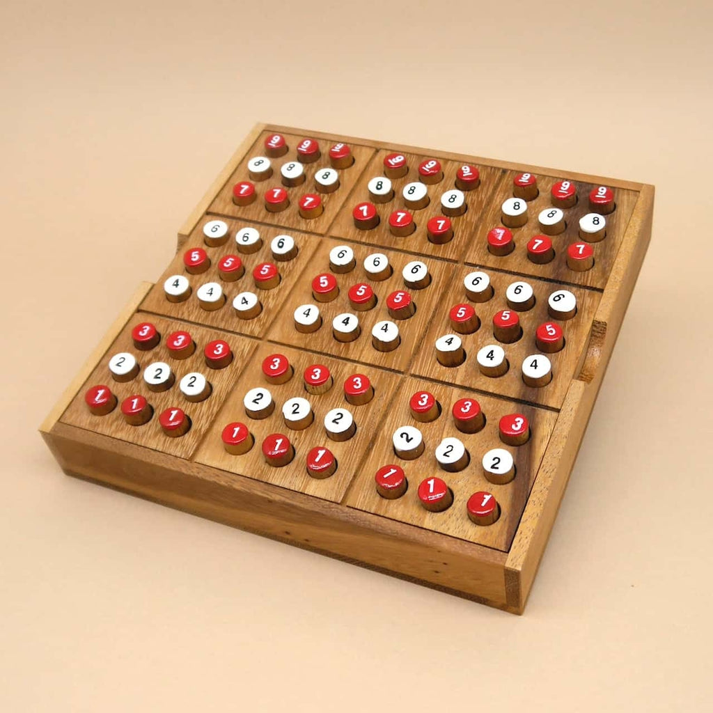 Komplett bestücktes Sudoku denkspiel aus Holz; rote und weiße Zahlenpins füllen alle neun Unterquadrate des quadratischen Spielbretts.
