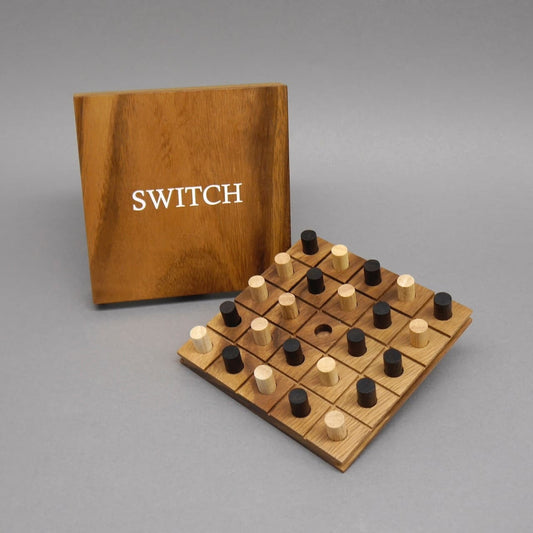 Holz-Brettspiel „Switch“: quadratisches Spielfeld mit schwarzen und naturfarbenen Stiften vor aufgeklapptem Brettdeckel.