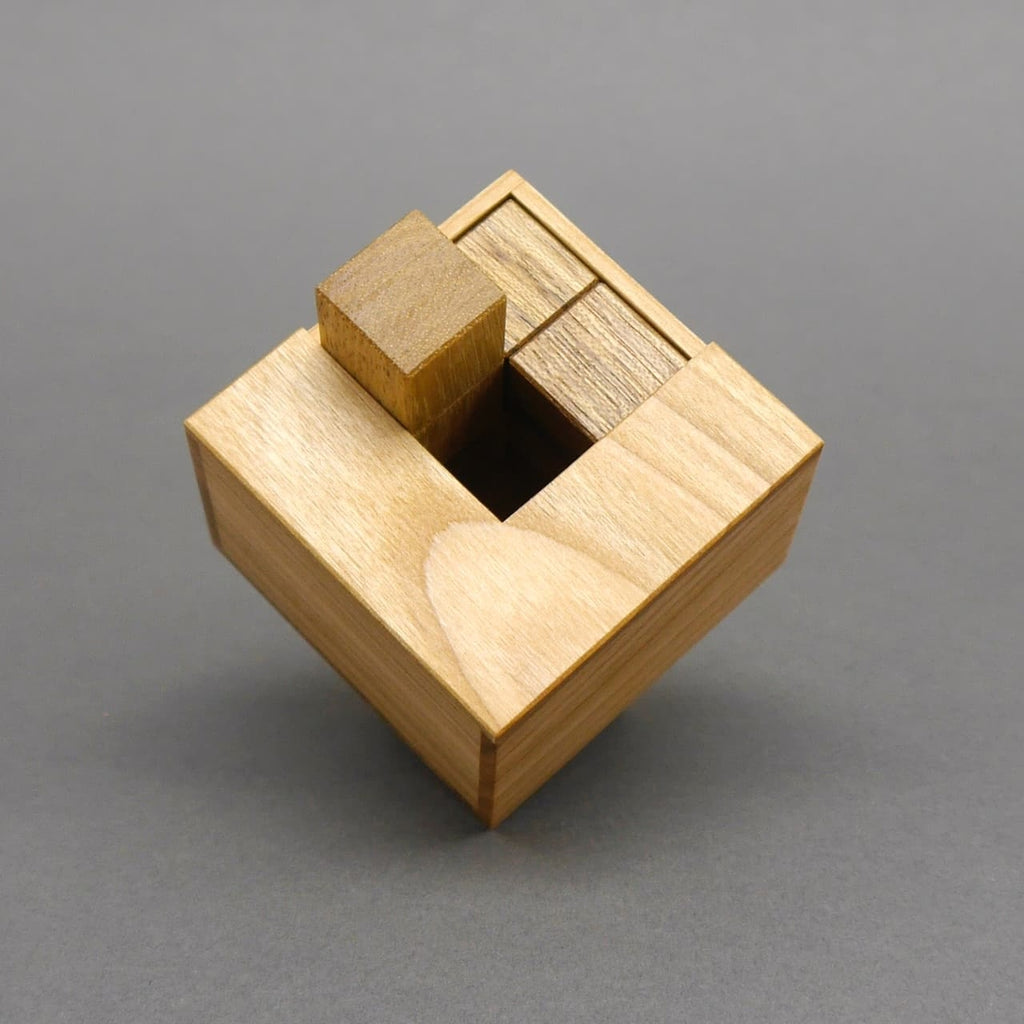  Zusammengesetzte Holzteile in einer quadratischen Holzkiste als Teil eines logischen Denkspiels.