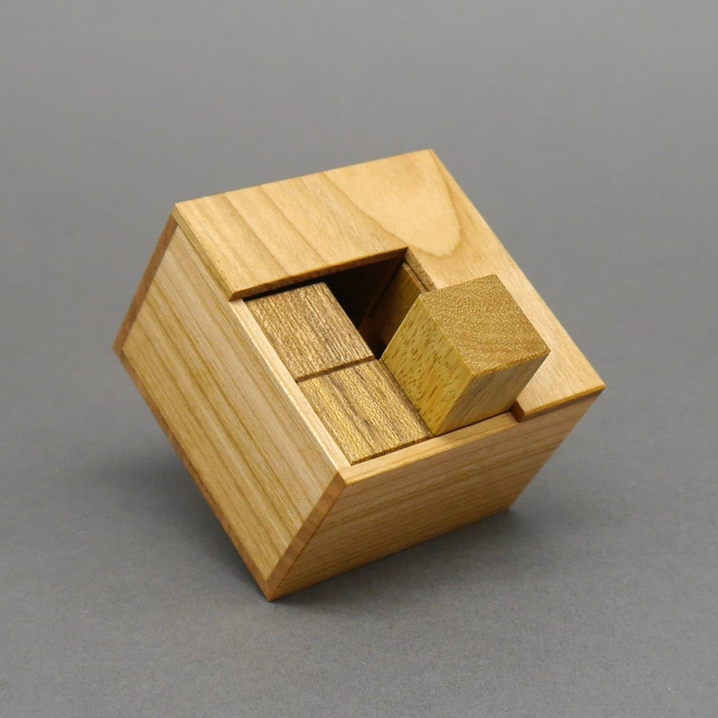 Perspektivische Ansicht eines fertigen Holzpuzzles in einer eckigen Kiste, bestehend aus verschiedenen Holzblöcken.