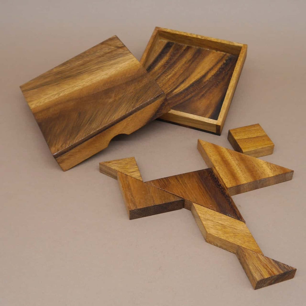 Geöffnete Holzbox mit auseinandergelegten Tangram-Formen, typisches Legepuzzle für Knobelfreunde.