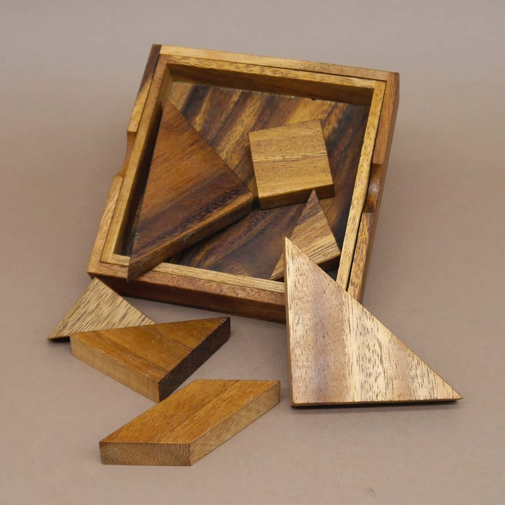 Tangram-Legefiguren neben einer Holzbox, ein klassisches Denkspiel zur Förderung der räumlichen Vorstellungskraft.