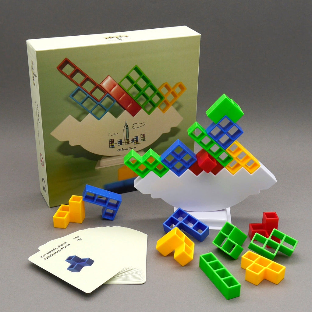 Buntes Gesellschaftsspiel mit Balancier-Steinen, Spielkarten und Verpackung auf grauem Hintergrund arrangiert.