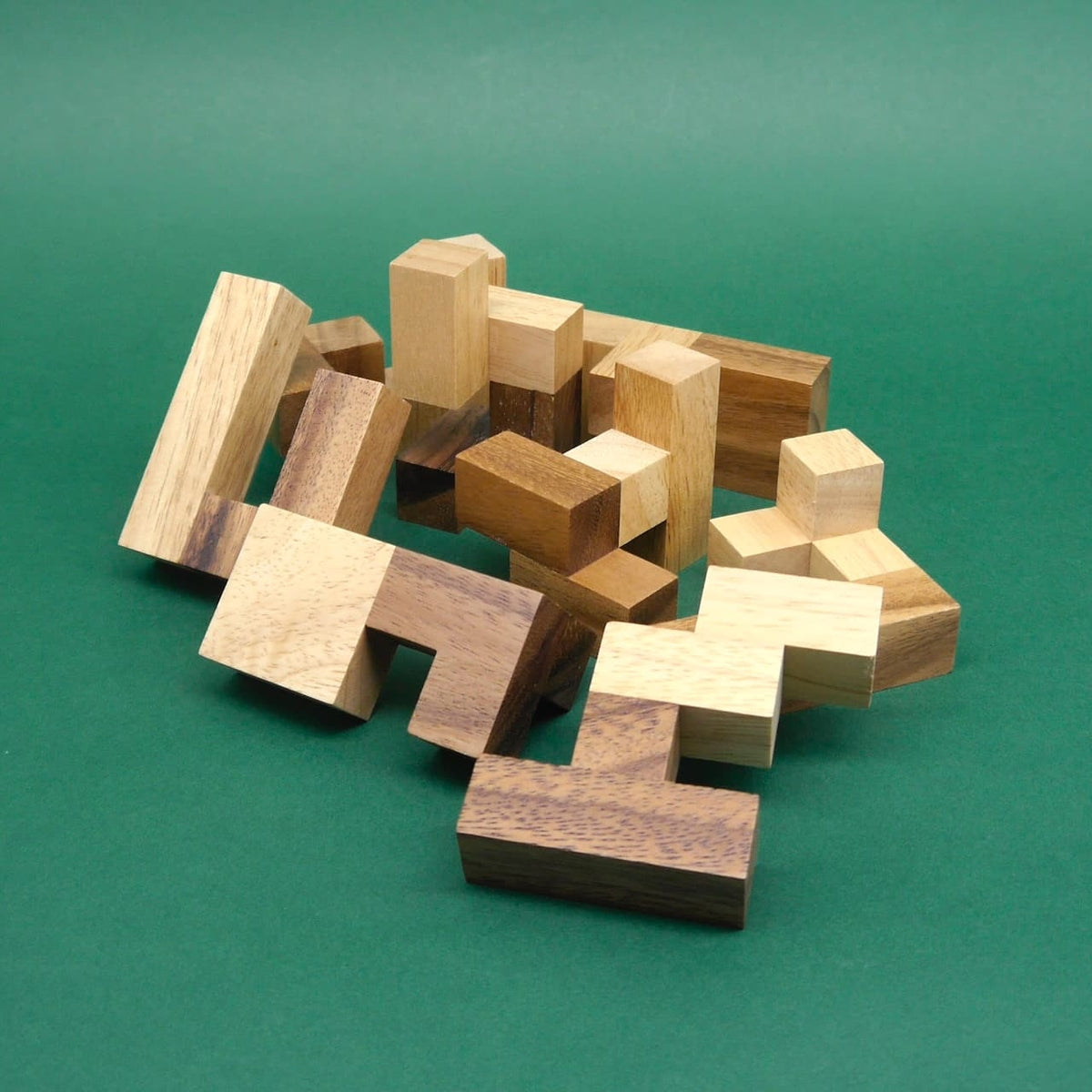 Durcheinanderliegende Holzmodule eines Knobelspiel bilden ein loses Geflecht auf dunkelgrünem Untergrund.