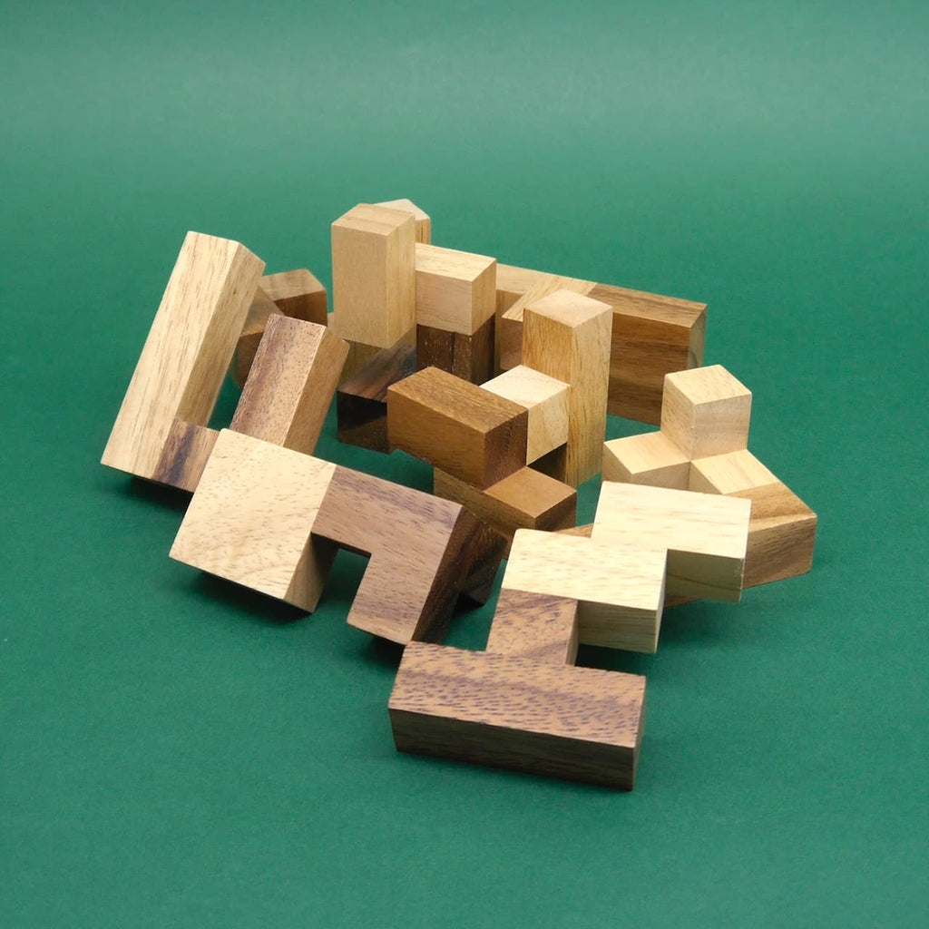 Durcheinanderliegende Holzmodule eines Knobelspiel bilden ein loses Geflecht auf dunkelgrünem Untergrund.
