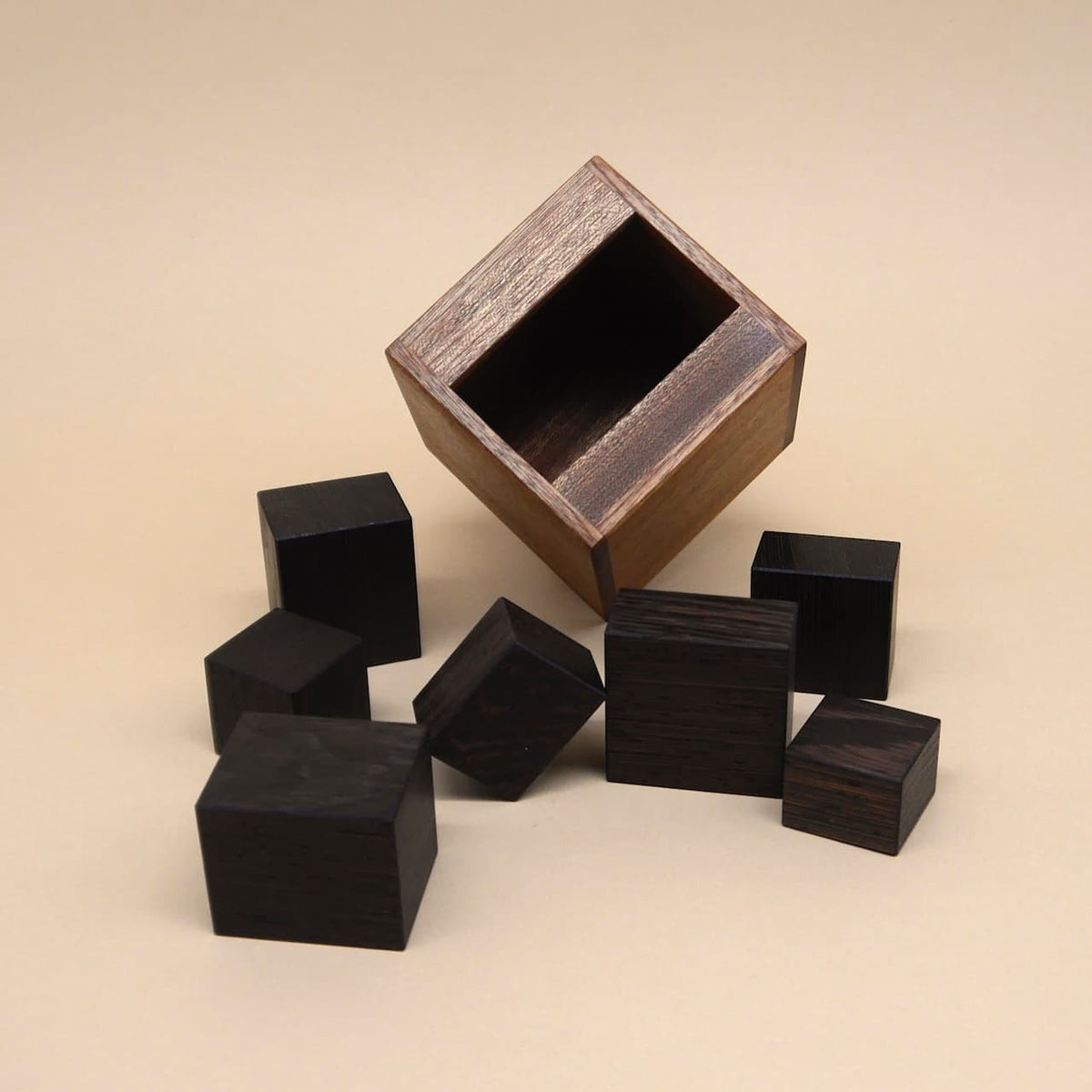 Geöffnete Knobelbox mit herausgenommenen schwarzen Würfeln als klassisches Packing Puzzle.
