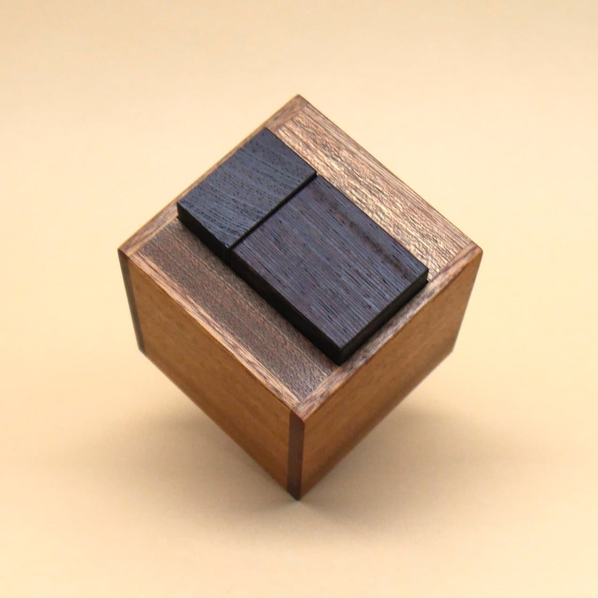Holzbox mit passgenau eingesetzten schwarzen Würfeln als kniffliges Logikpuzzle und Geduldspiel.