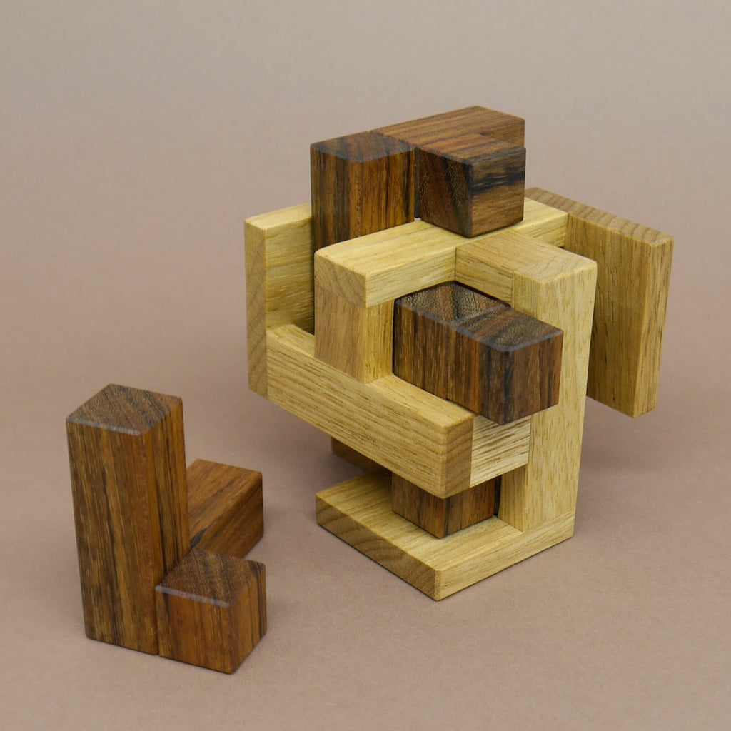Holzpuzzle mit mehreren passgenauen Teilen in Naturholz-Optik, die zu einem kompakten Würfel zusammengesetzt werden können. Ein kniffliges Denkspiel zur Förderung von Konzentration und räumlichem Vorstellungsvermögen.