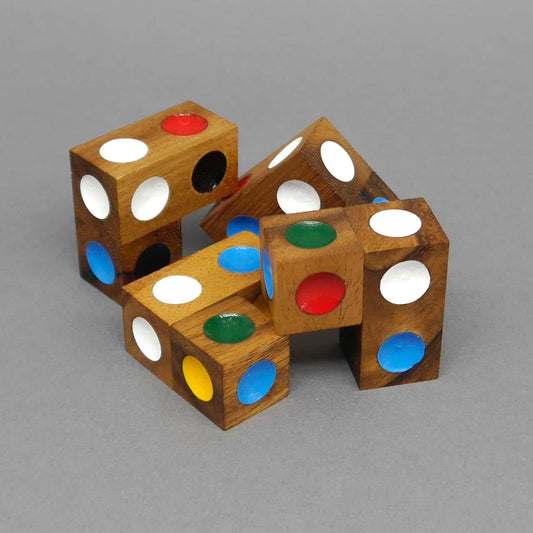 Mehrere locker zusammengesteckte Holz­würfel mit bunten Punkten bilden ein Legepuzzle auf grauem Hintergrund.