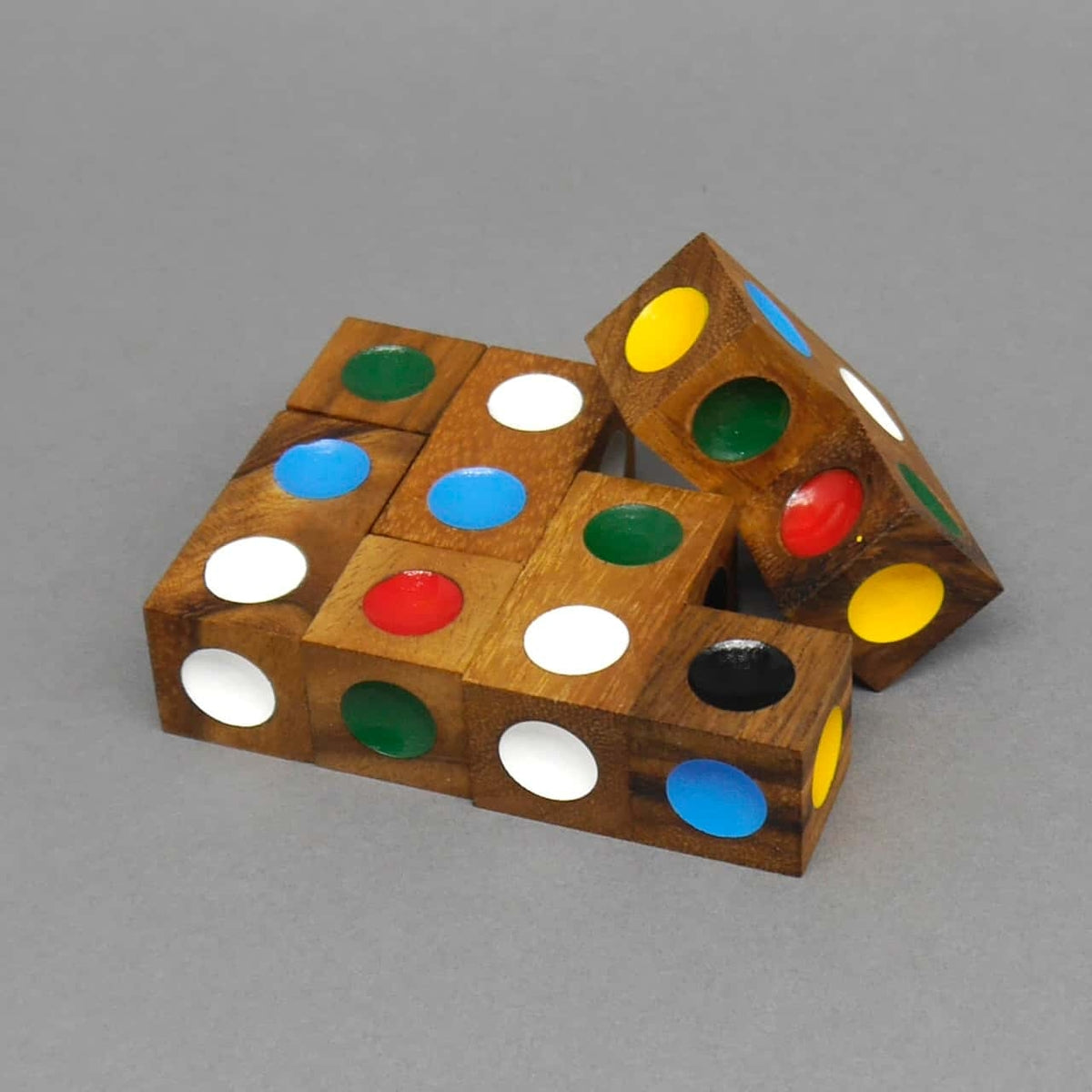 Flach angeordnetes Logikpuzzle aus Holz­würfeln mit farbigen Punkt-Einlässen, das ein rechteckiges Muster ergibt.