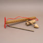 Knobelspiel aus Holz mit mehreren Bauteilen und roter Kordel als klassisches Geduldsspiel.