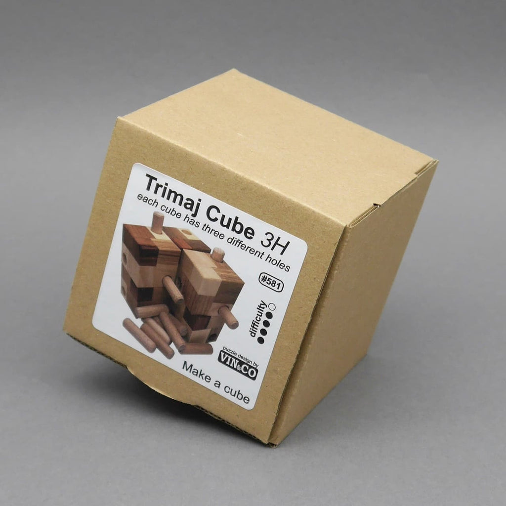 Verpackung des Trimaj Cube 3H, einem Logikspiel aus Holz, mit Produktlabel und teilweise sichtbarem Würfelmotiv auf einer schräg stehenden Kartonschachtel.