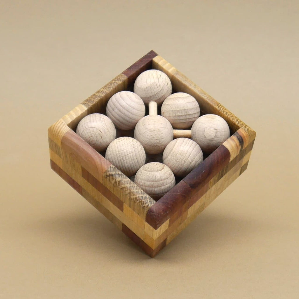 Quadratische Holzbox randvoll mit kugelförmigen Modulen, dicht verstaut; Fokus auf Holzmaserung und saubere Verarbeitung, neutraler Hintergrund.