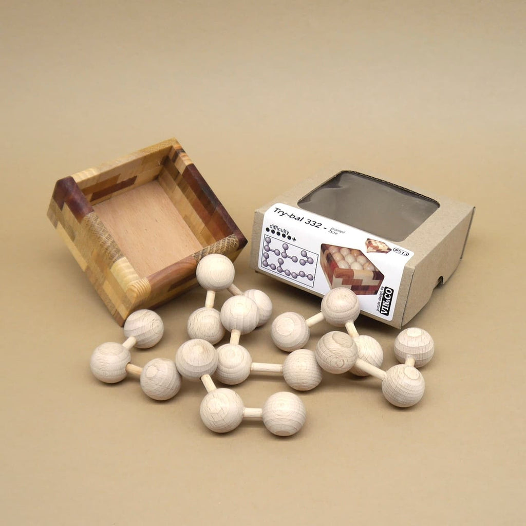 Offene Holzbox, daneben mehrgliedrige Kugel-Stab-Kette des Try-bal 332, rechts der Produktkarton; naturbelassenes Holz auf beigem Hintergrund.