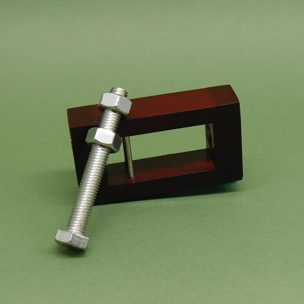Knobelpuzzle: Horizontal liegender Holzrahmen mit vorgelagerter Metallschraube samt Muttern – mechanisches Rätsel für Fans des Knobeln.