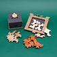 Dreiteiliges Holzpuzzle-Set „Virus in a Box“ mit einer geschlossenen Puzzlebox, einer Spielfläche mit eingelegten weißen Teilen und sortierten Puzzleteilen in drei Farben.
