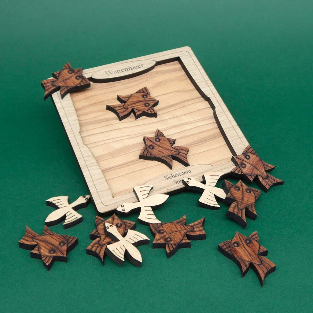 Verschiedene hölzerne Puzzle-Elemente eines Knobelspiels im Wattenmeer-Design, ausgebreitet auf einer glatten Oberfläche.