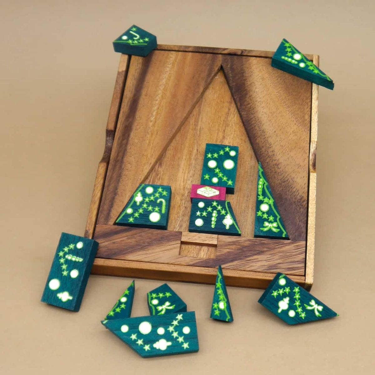 Holzrahmen mit grün bedruckten Puzzleteilen in Tannenform, teilweise eingelegt – ein weihnachtliches Denkspiel.