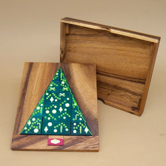 Fertig gelegter grüner Weihnachtsbaum als Legepuzzle auf Holzbrett; der Deckel der Box steht daneben.