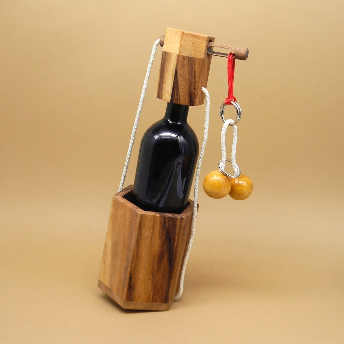 Holz-Knobelspiel hält eine Weinflasche zwischen zwei sechseckigen Blöcken; Kordel mit Holzkugeln und Ringen sichert den Verschluss.