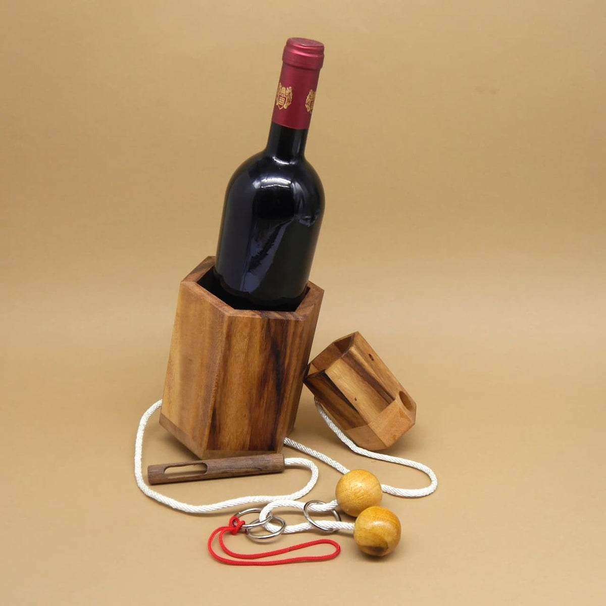 Weinflasche halb im Holzbehälter; Teile des Flaschentresors und die Kordel liegen daneben als originelle Geschenkidee.