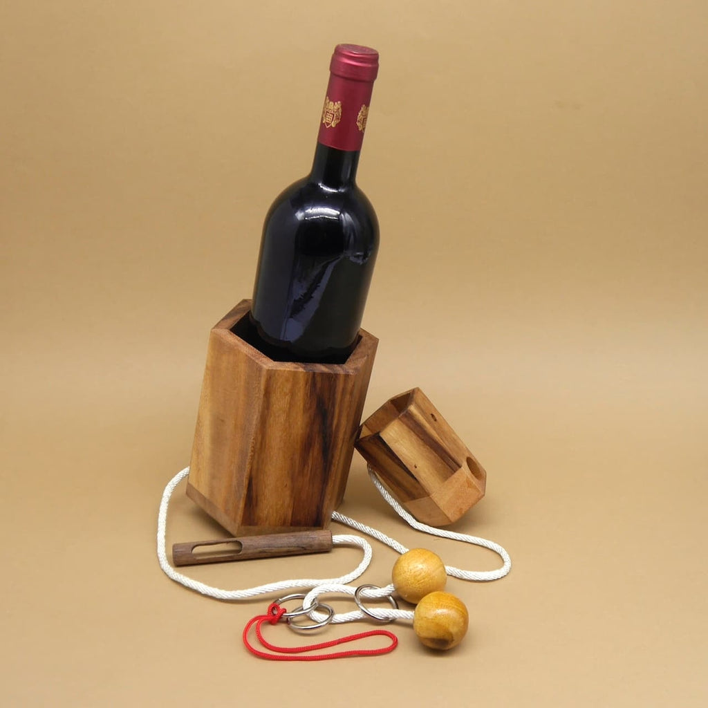 Weinflasche halb im Holzbehälter; Teile des Flaschentresors und die Kordel liegen daneben als originelle Geschenkidee.