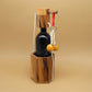 Aufgebautes Geduldspiel: Weintresor aus Holz mit Kordeln, Ringen und zwei Holzkugeln; sichert eine dunkle Weinflasche.