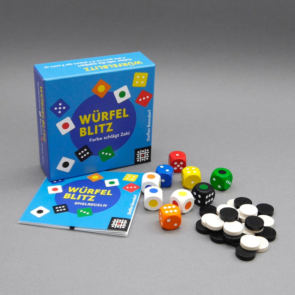 Spiel Würfelblitz mit Schachtel, Anleitung, bunten Würfeln und Spielsteinen, übersichtlich auf grauer Fläche arrangiert.