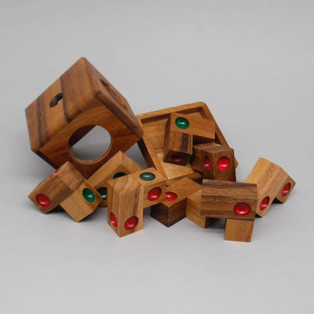 Holz­teile eines IQ-Puzzle sind aus der Würfelbox herausgekippt; rote und grüne Punkte an den Stücken warten darauf, zum 3D-Würfel zusammengesetzt zu werden.