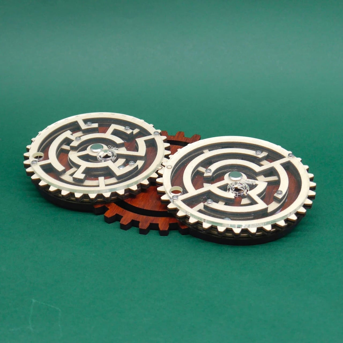 Geduldsspiel Zahnradlabyrinth mit zwei runden Scheibenrädern aus Holz und Acryl, schräg fotografiert auf grünem Untergrund