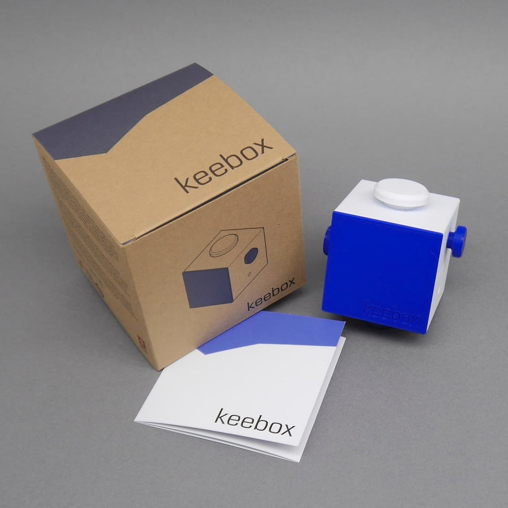 Keebox blue Denkspiel: Rätsel-Box mit Verpackung und Anleitung im Set arrangiert.