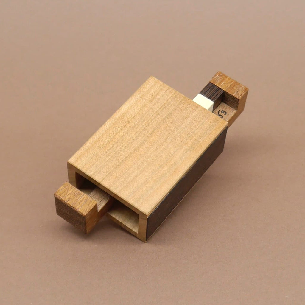 Holzpuzzle in Form einer rechteckigen Schachtel mit zwei hervorstehenden Holzteilen – ein Denkspiel aus hellem und dunklem Holz.