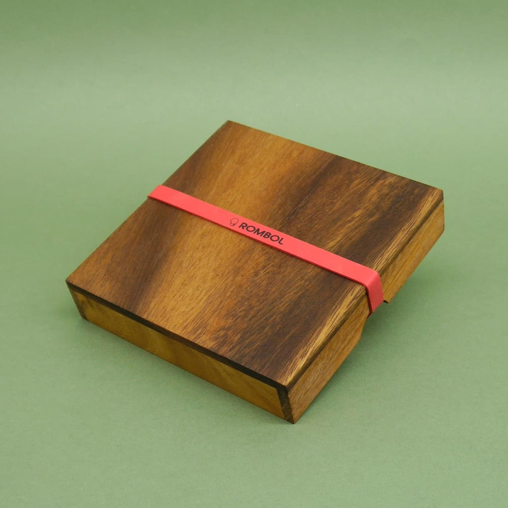 Quadratische Holzbox mit Deckel und rotem Band – minimalistisches Design für ein Geduldspiel.