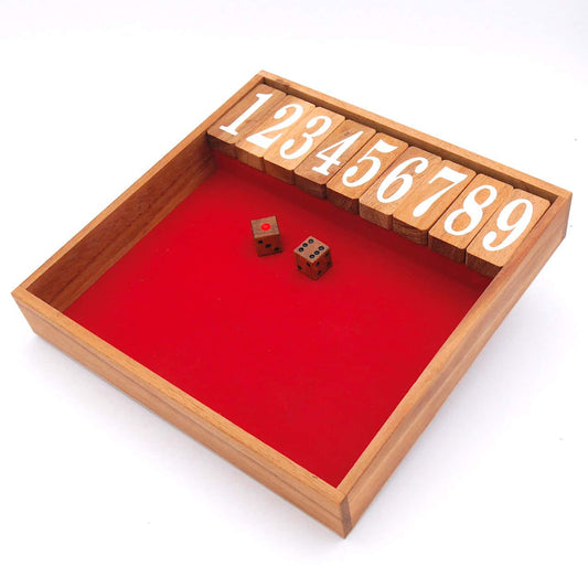 Das Würfelspiel Shut the box aus Holz mit rotem Flies bezogen und zwei Würfeln.
